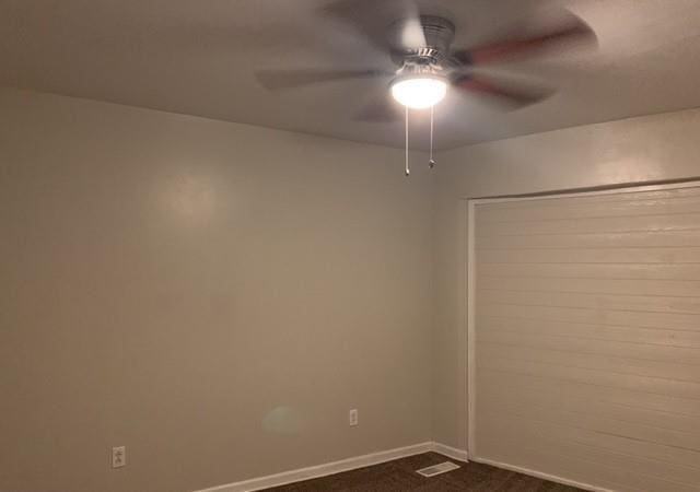 unfurnished room featuring dark carpet, a ceiling fan, and baseboards