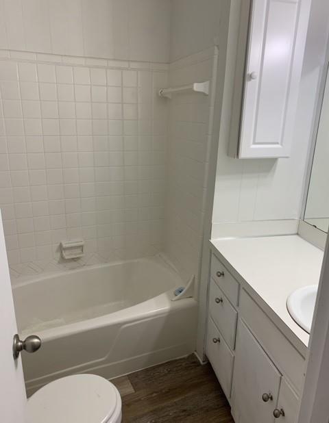 full bath with vanity, bathing tub / shower combination, toilet, and wood finished floors