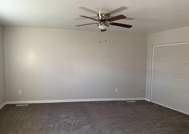 unfurnished room with dark carpet, a ceiling fan, and baseboards