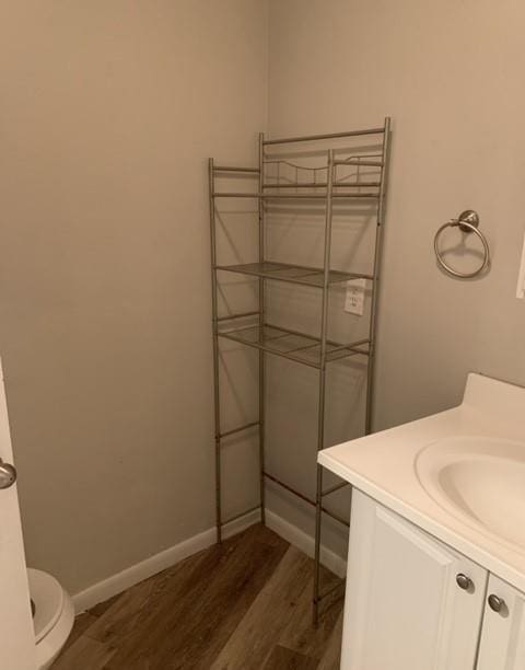 bathroom featuring vanity, baseboards, wood finished floors, and toilet