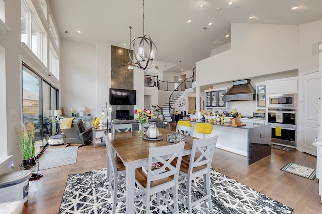 dining space with a high ceiling, stairs, wood finished floors, and a notable chandelier