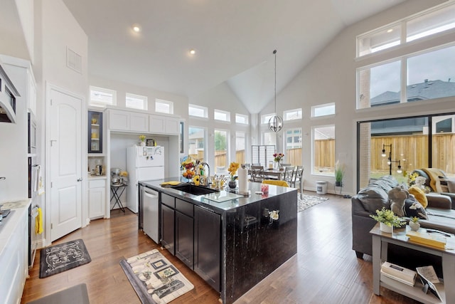 kitchen featuring wood finished floors, white appliances, open floor plan, high vaulted ceiling, and a sink