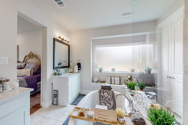 ensuite bathroom with tile patterned flooring, a freestanding bath, visible vents, and vanity