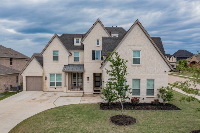 french provincial home with driveway, roof with shingles, brick siding, a front lawn, and an attached garage