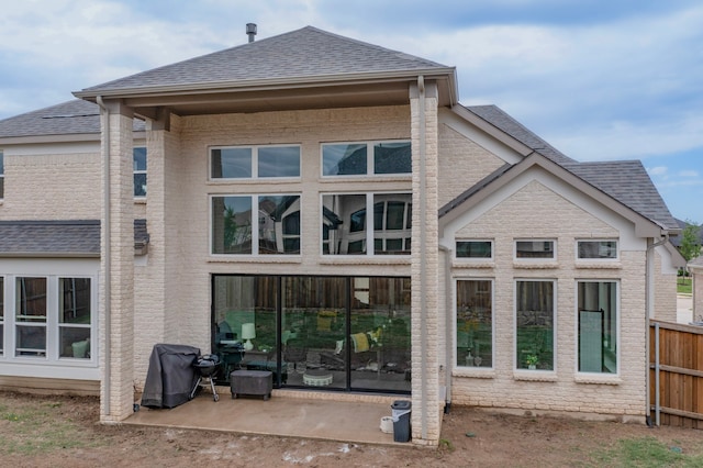 back of house featuring brick siding, fence, and a shingled roof
