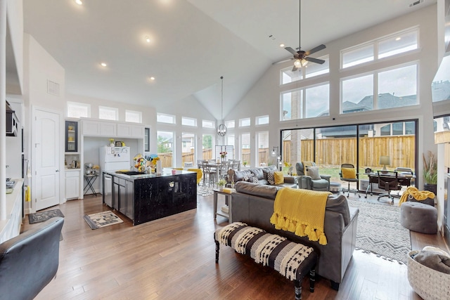 living area with light wood-type flooring, a ceiling fan, recessed lighting, and high vaulted ceiling