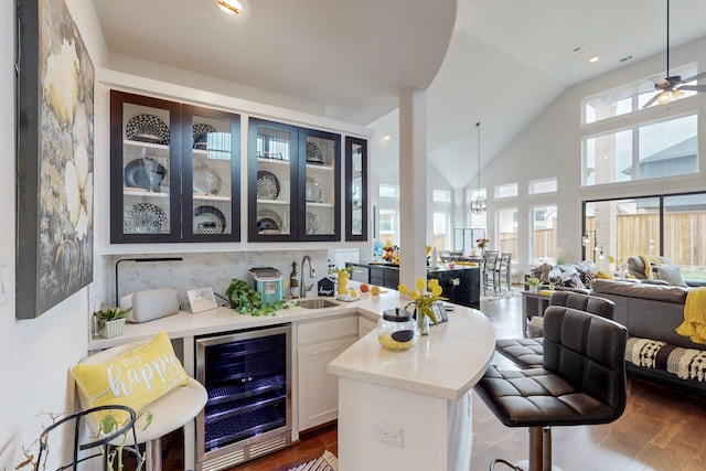 bar with beverage cooler, a sink, decorative backsplash, and dark wood-type flooring