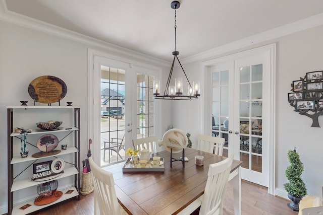 dining space with crown molding, a notable chandelier, french doors, and wood finished floors