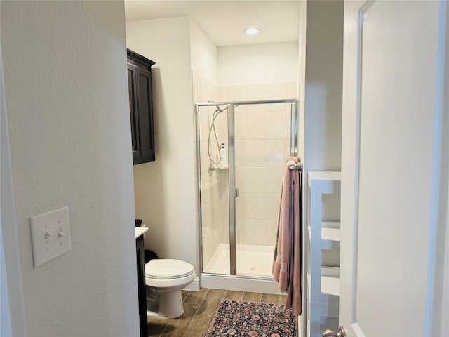 full bathroom featuring vanity, wood finished floors, toilet, and a shower stall