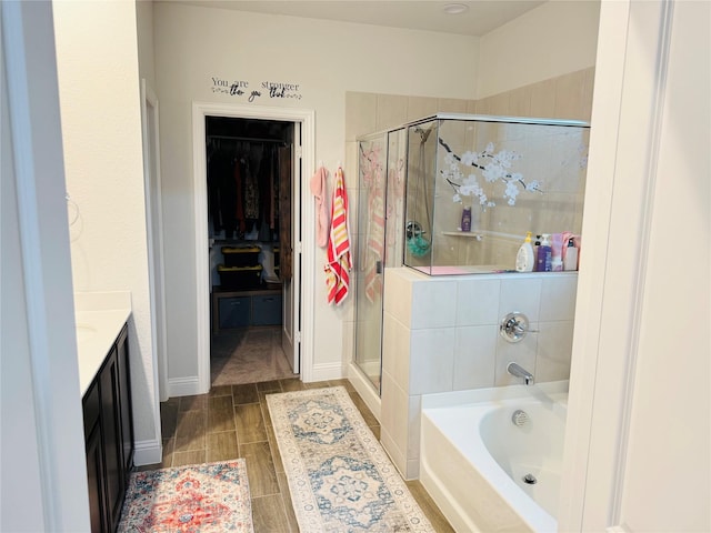 bathroom with vanity, a walk in closet, a bath, and a stall shower