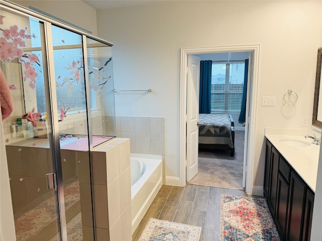 bathroom with vanity, wood finished floors, baseboards, a bath, and a stall shower