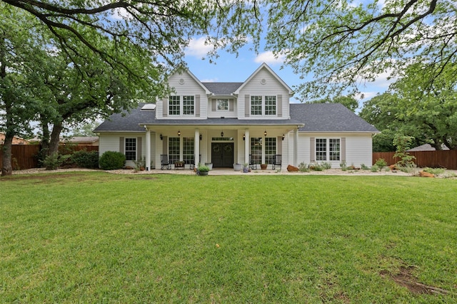 view of front of property featuring roof with shingles, fence, and a front yard