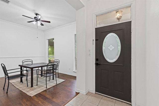 foyer featuring a ceiling fan, visible vents, wood finished floors, baseboards, and ornamental molding