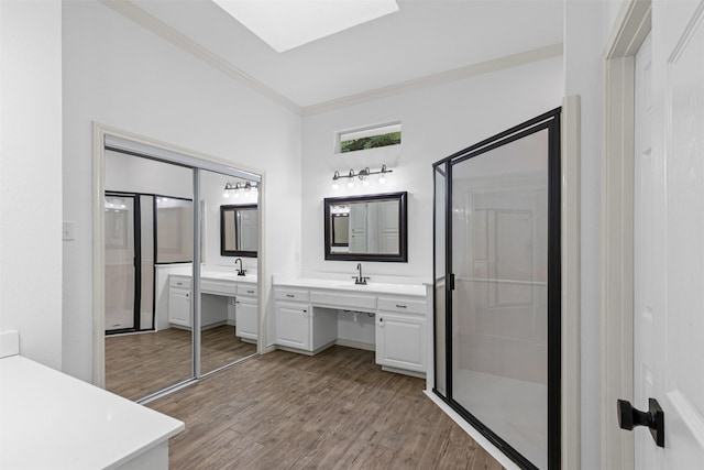 full bathroom featuring a skylight, walk in shower, wood finished floors, vanity, and ornamental molding