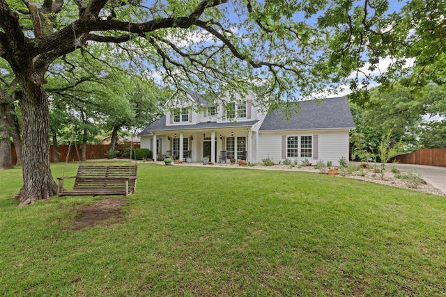 rear view of house featuring a lawn, fence, and roof with shingles