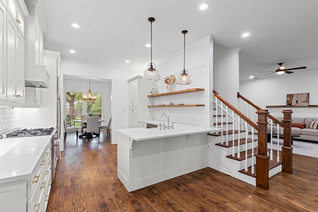 kitchen featuring dark wood-style flooring, a peninsula, white cabinetry, tasteful backsplash, and ceiling fan with notable chandelier