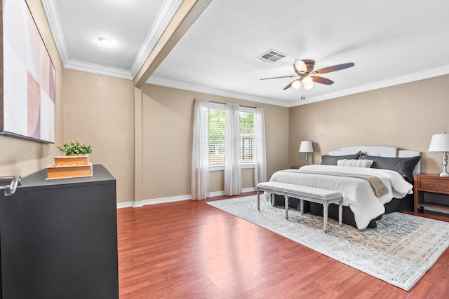 bedroom featuring crown molding, baseboards, visible vents, and wood finished floors