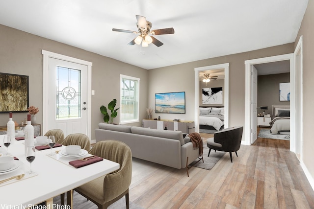 living area featuring baseboards, ceiling fan, and light wood-type flooring