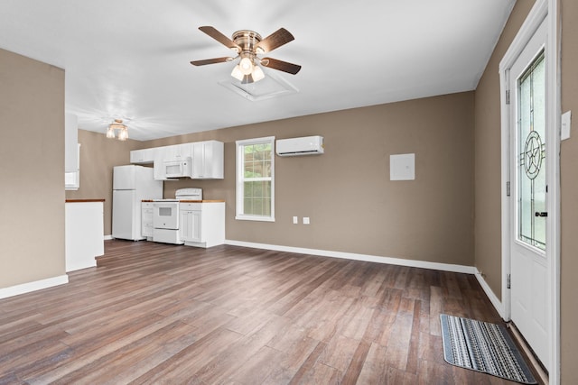 unfurnished living room featuring baseboards, a wall unit AC, a ceiling fan, and dark wood-type flooring