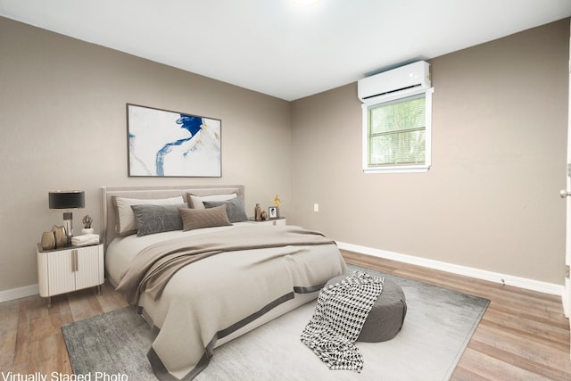 bedroom with baseboards, a wall unit AC, and light wood-type flooring