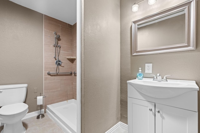 bathroom featuring a shower stall, vanity, tile patterned floors, baseboards, and toilet