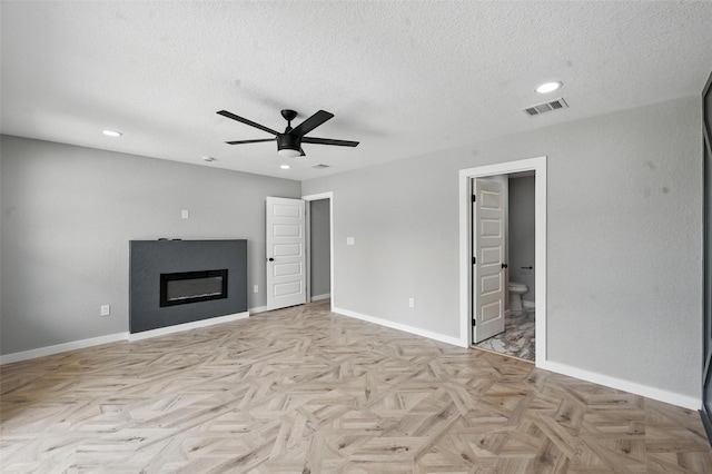 unfurnished living room featuring a textured ceiling, ceiling fan, visible vents, and a glass covered fireplace