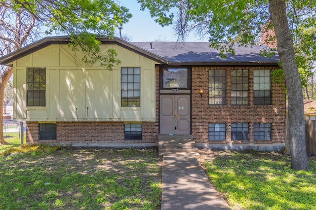 view of front of home featuring brick siding, a front lawn, and fence