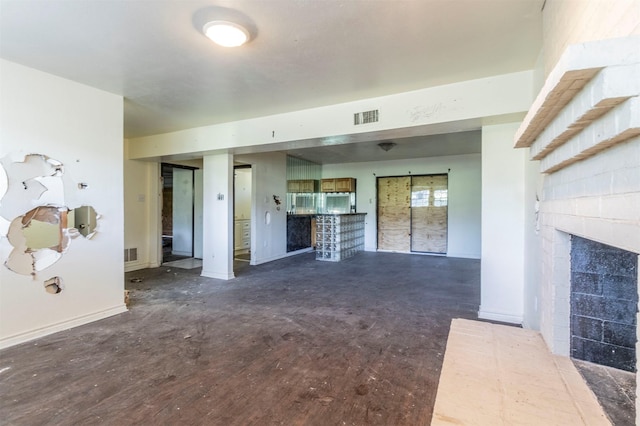 unfurnished living room with baseboards, a fireplace, dark wood-type flooring, and visible vents