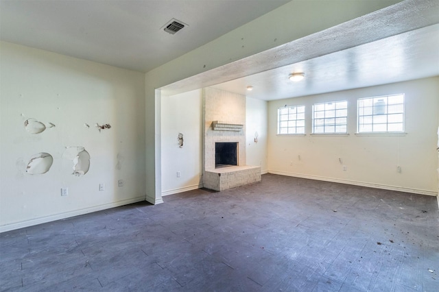 unfurnished living room featuring a brick fireplace, baseboards, and visible vents