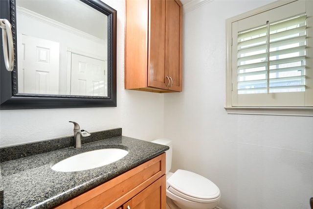 half bath with vanity, ornamental molding, and toilet