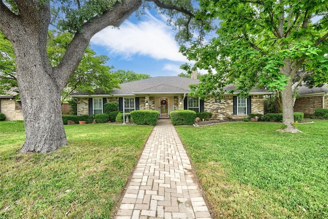 ranch-style home with a chimney, a front lawn, and brick siding