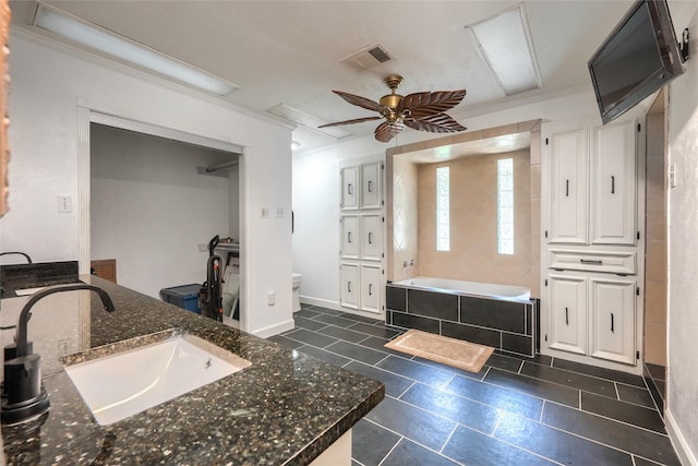 bathroom featuring ceiling fan, a bath, visible vents, vanity, and toilet