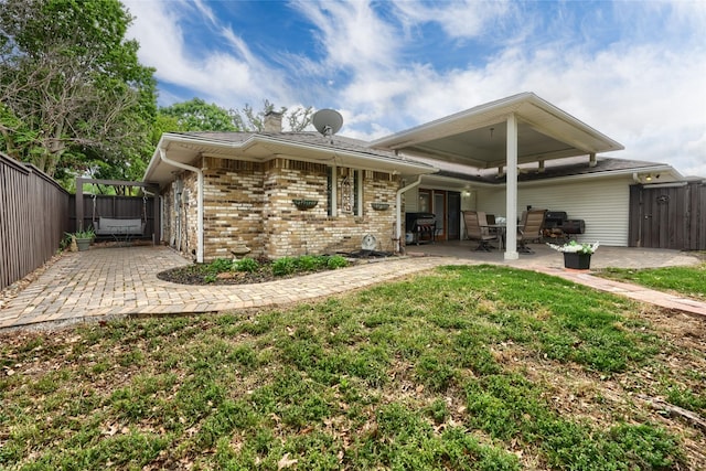 back of house featuring brick siding, a chimney, a fenced backyard, and a patio area