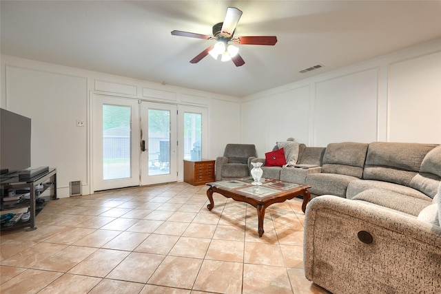 living room featuring ceiling fan, visible vents, light tile patterned floors, and a decorative wall