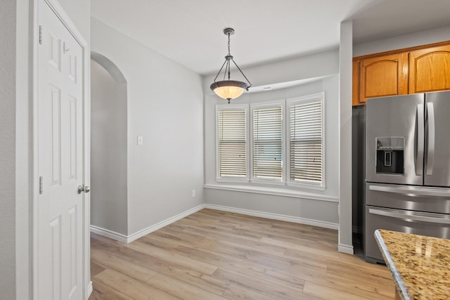 689 Bonham Dr, Lavon, TX 75166 - interior space featuring arched walkways, baseboards, stainless steel fridge, and light wood finished floors
