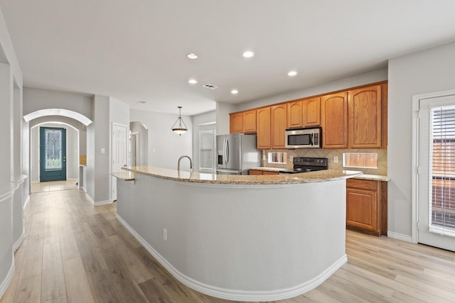 689 Bonham Dr, Lavon, TX 75166 - kitchen featuring light wood-type flooring, arched walkways, appliances with stainless steel finishes, and recessed lighting