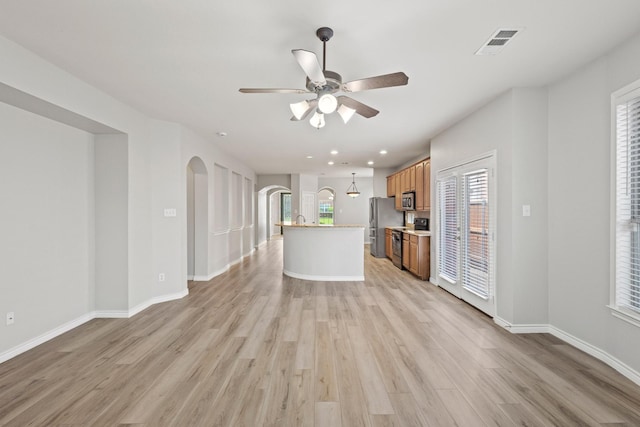 689 Bonham Dr, Lavon, TX 75166 - kitchen featuring brown cabinetry, visible vents, arched walkways, light wood-style floors, and stainless steel appliances