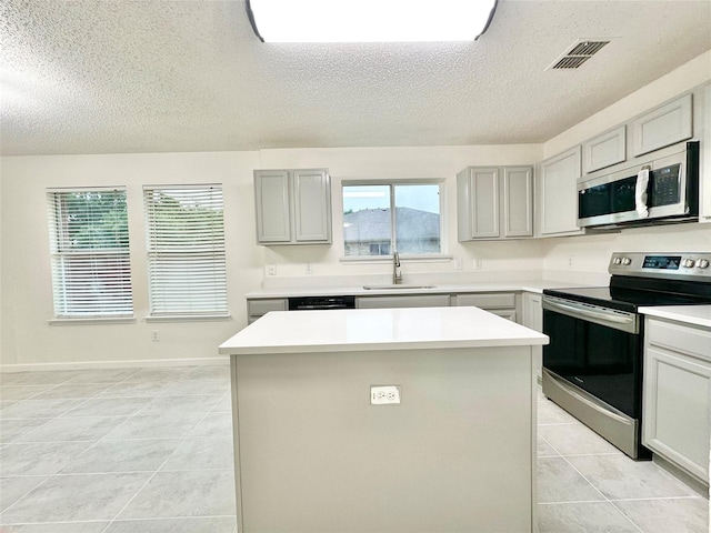 kitchen featuring a sink, gray cabinets, stainless steel appliances, and a textured ceiling