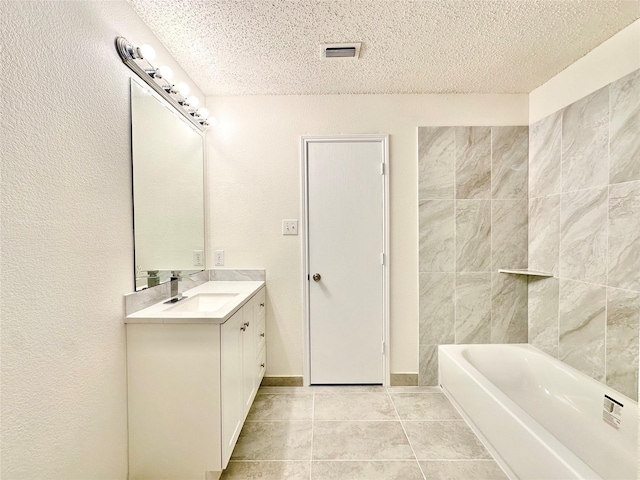 full bath featuring vanity, a bathing tub, a textured ceiling, tile patterned floors, and visible vents