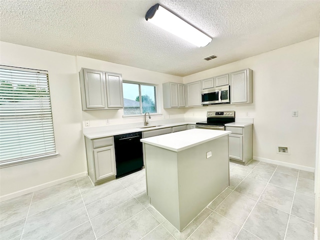 kitchen featuring gray cabinets, a textured ceiling, a center island, light tile patterned floors, and stainless steel appliances