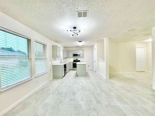 kitchen featuring a textured ceiling, visible vents, light countertops, gray cabinetry, and stainless steel appliances