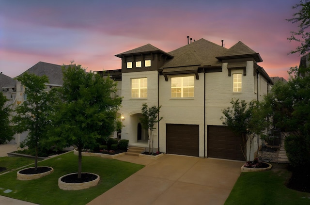 view of front of house with an attached garage, a front lawn, roof with shingles, and driveway