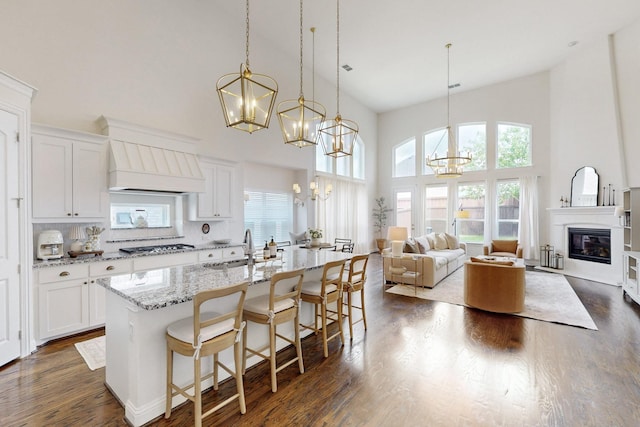 kitchen with high vaulted ceiling, a chandelier, a sink, and custom range hood