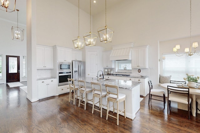 kitchen with appliances with stainless steel finishes, a sink, high vaulted ceiling, a notable chandelier, and custom range hood