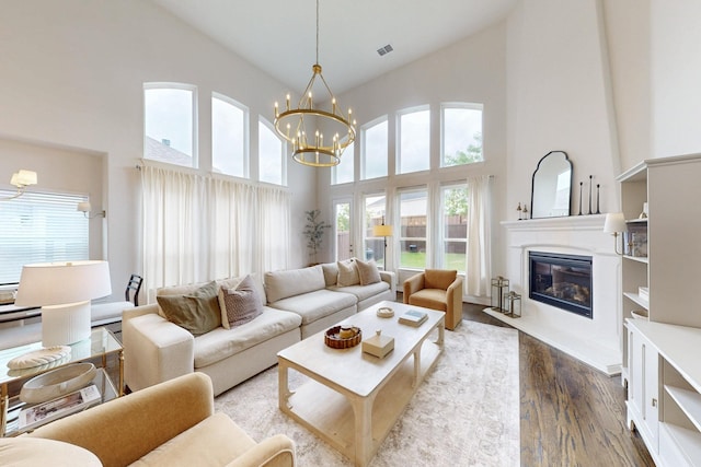living room with a high ceiling, a chandelier, a healthy amount of sunlight, and wood finished floors