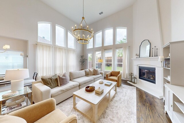 5936 Augustine Rd, Mckinney, TX 75071 - living area with a chandelier, a high ceiling, wood finished floors, healthy amount of natural light, and a glass covered fireplace