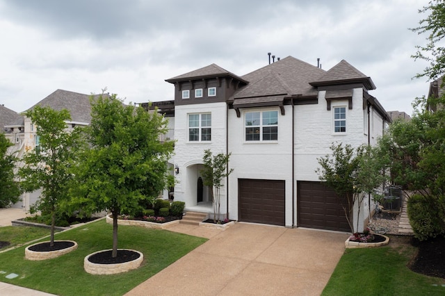 view of front of house with a garage, a front lawn, a shingled roof, and concrete driveway