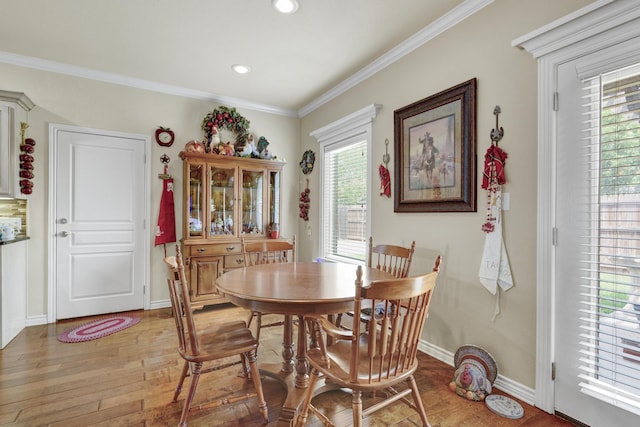 dining space with light wood-style floors, baseboards, plenty of natural light, and crown molding