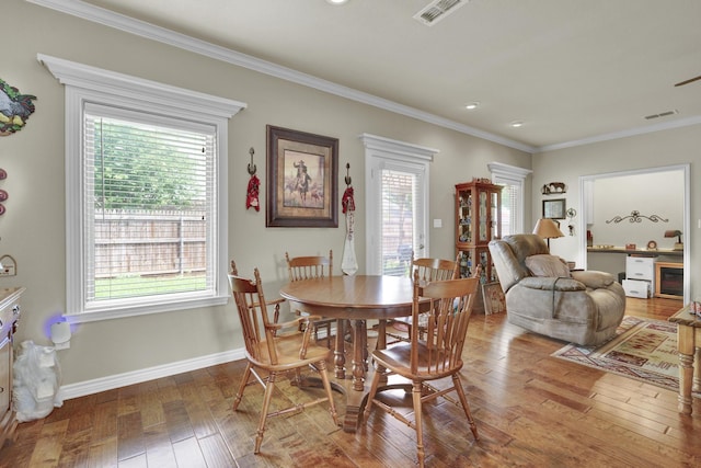 dining area with visible vents, ornamental molding, wood-type flooring, and a healthy amount of sunlight