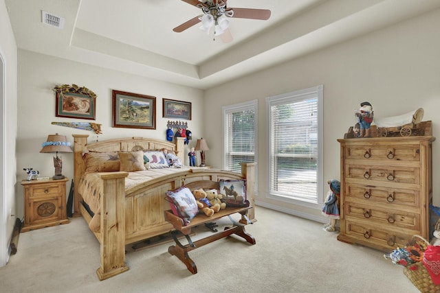 bedroom featuring a tray ceiling, ceiling fan, light colored carpet, and visible vents